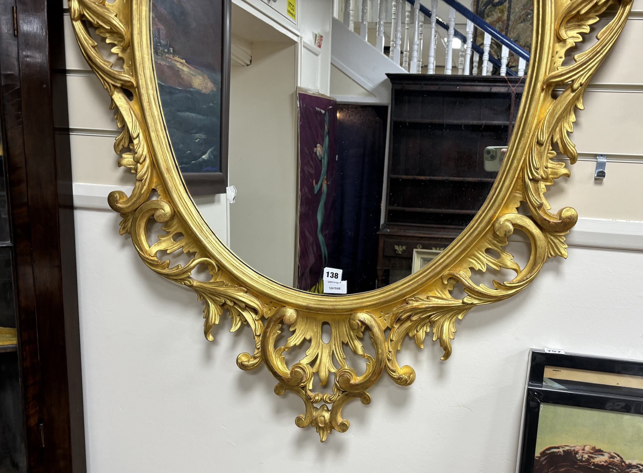A George III style carved giltwood oval wall mirror, width 89cm, height 160cm